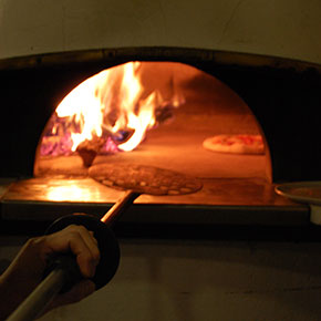 石窯でピッツァを焼いています。左は薪、右側が焼くスペースです